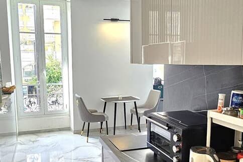 Cuisine en marbre sombre et coin repas devant une fenêtre à balcon