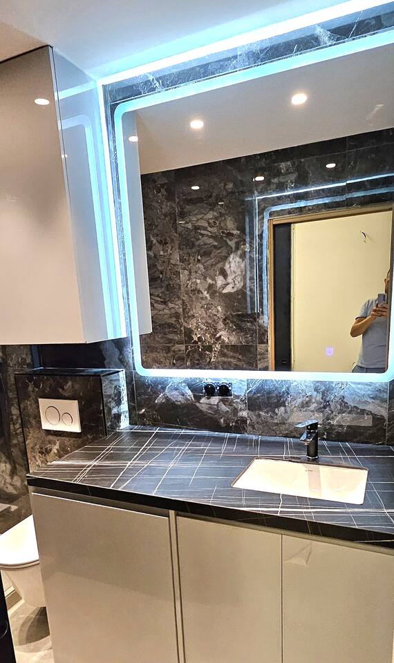 Dark marble washbasin with backlit mirror in the shower room
