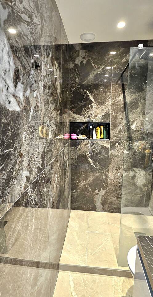 Walk-in shower clad in dark marble