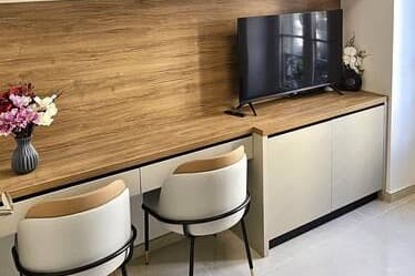 Plan de travail en bois adossé à une crédence, avec deux chaises et un téléviseur